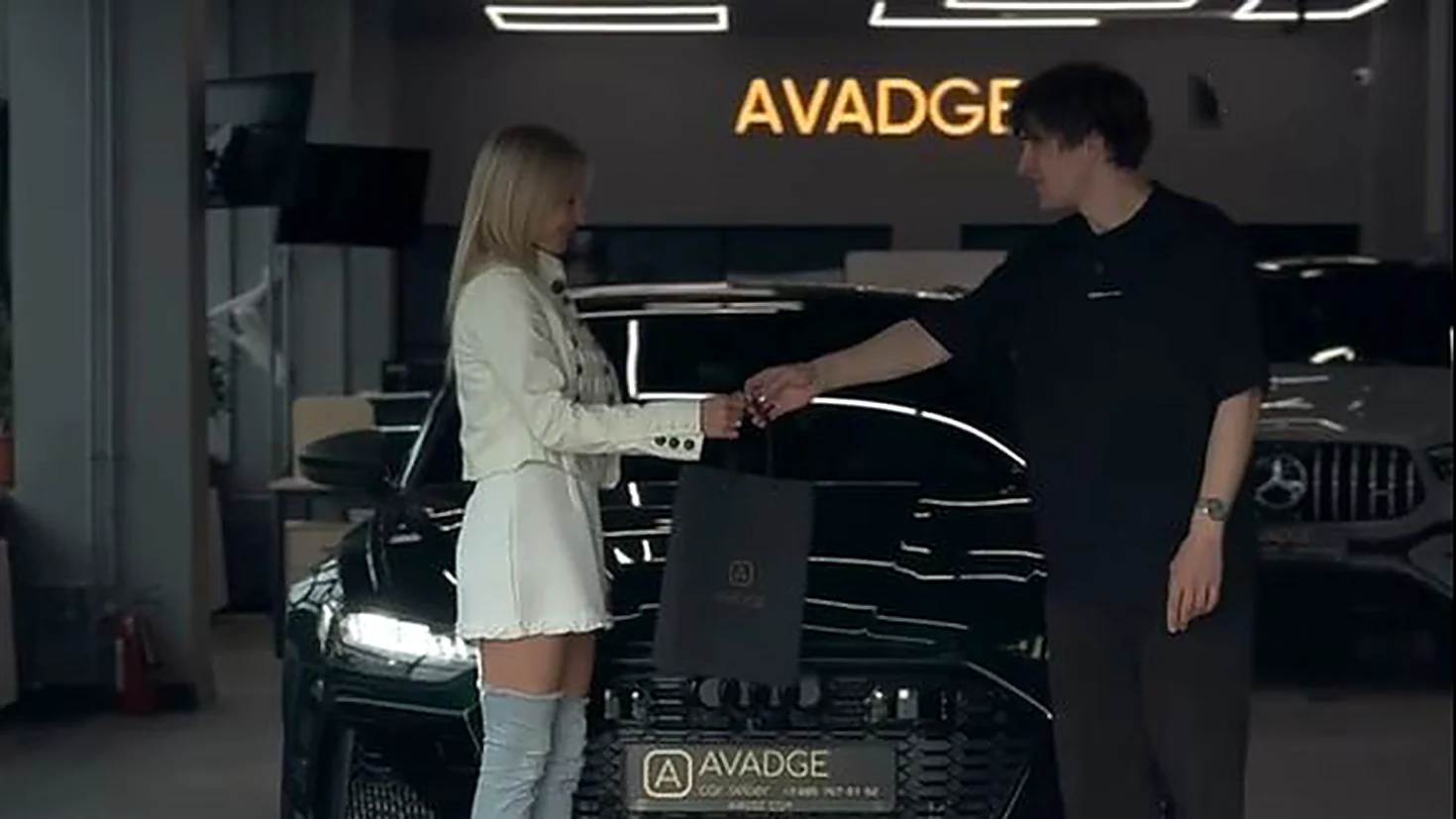 Менеджер AVADGE передаёт клиентке ключи от автомобиля в автосалоне