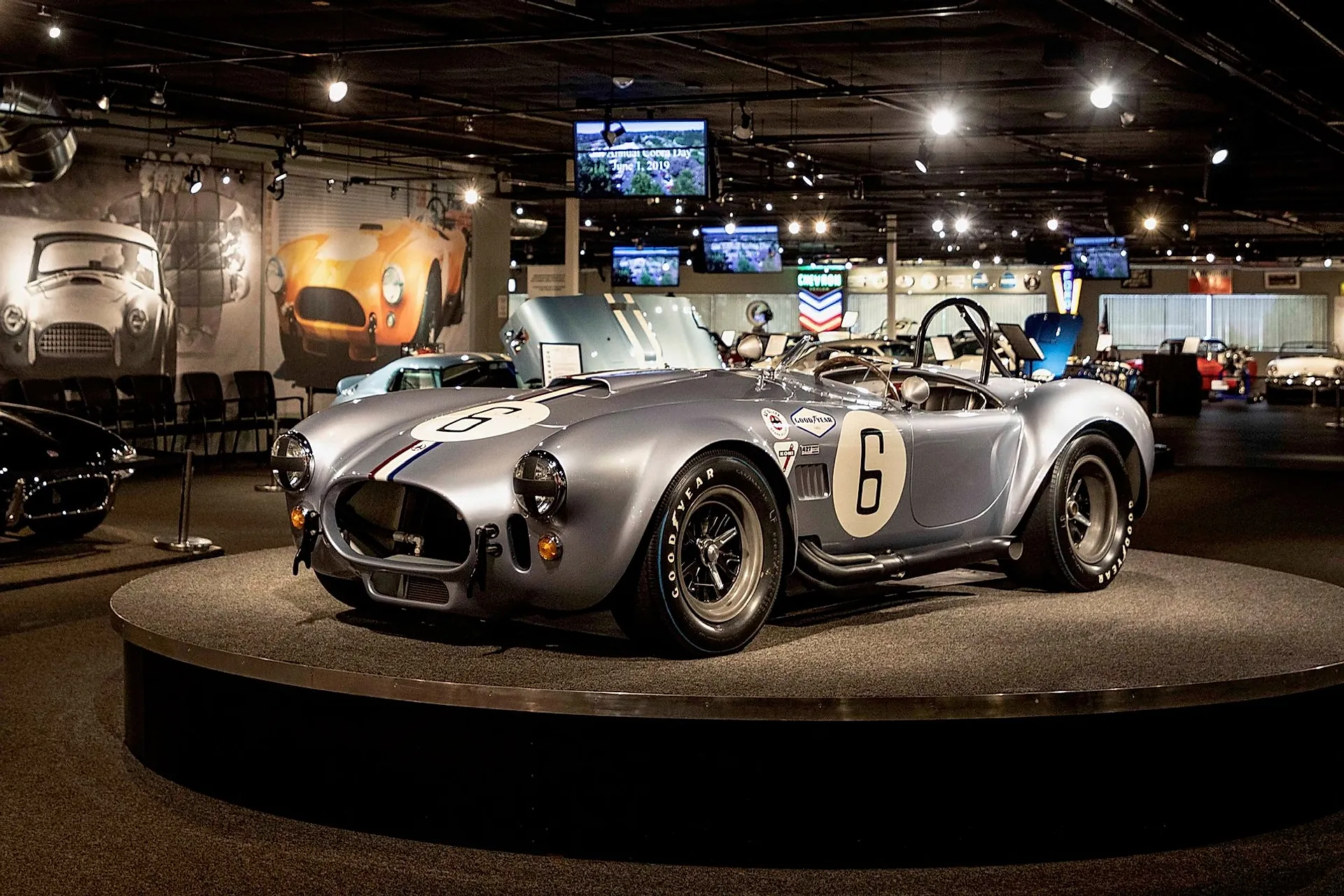 Гоночная AC Cobra 427 с номером 6 на подиуме в музее, вид спереди сбоку