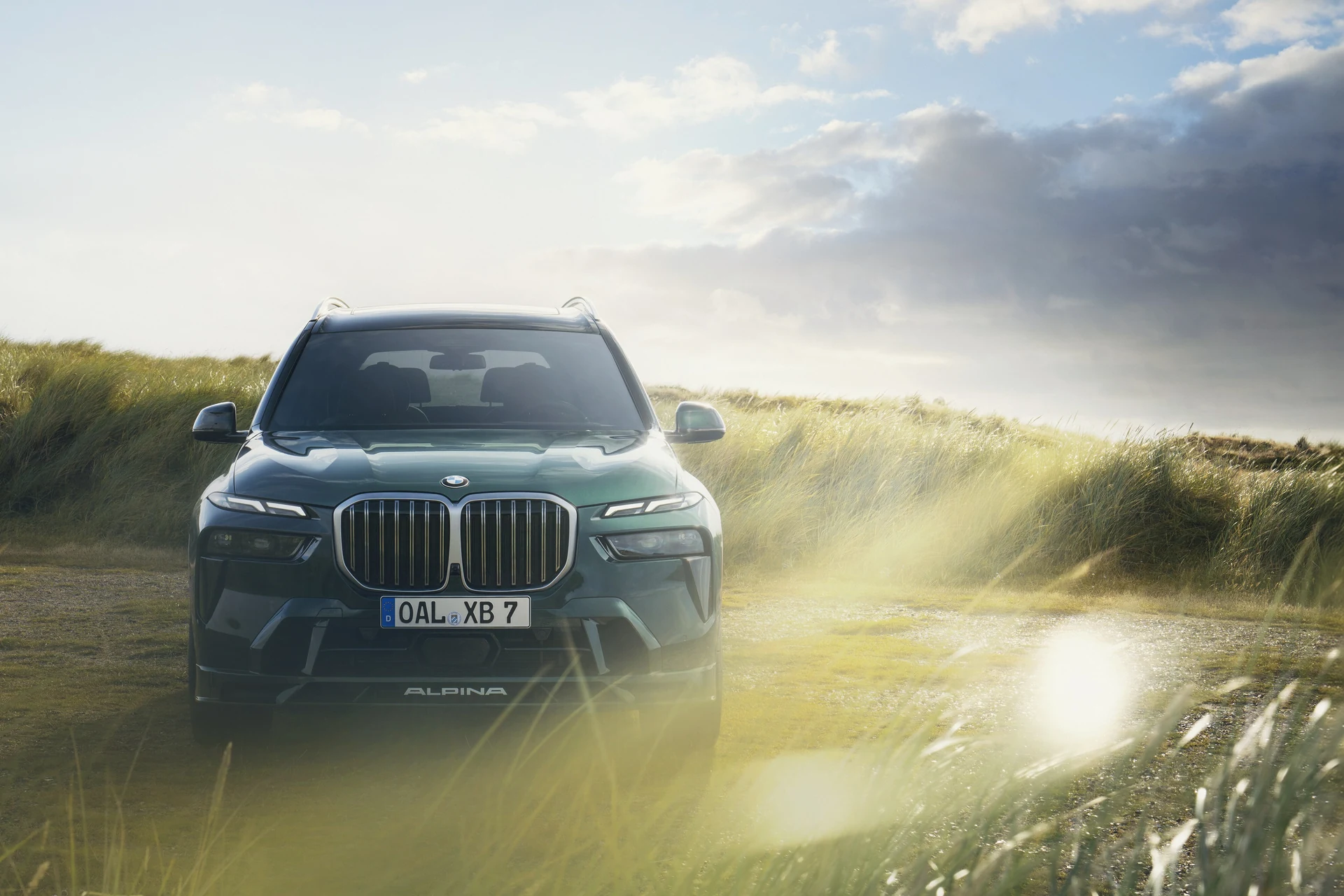 BMW ALPINA XB7 в цвете Alpina Green едет по прямой дороге среди дюн, вид анфас, ровный горизонт