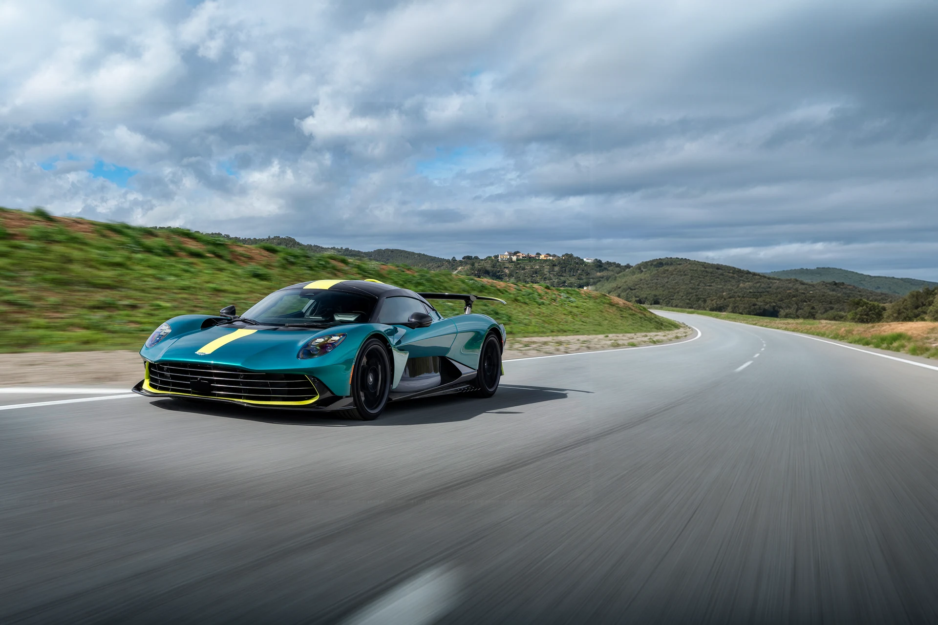 Гиперкар Aston Martin Valhalla в движении по трассе, вид спереди сбоку