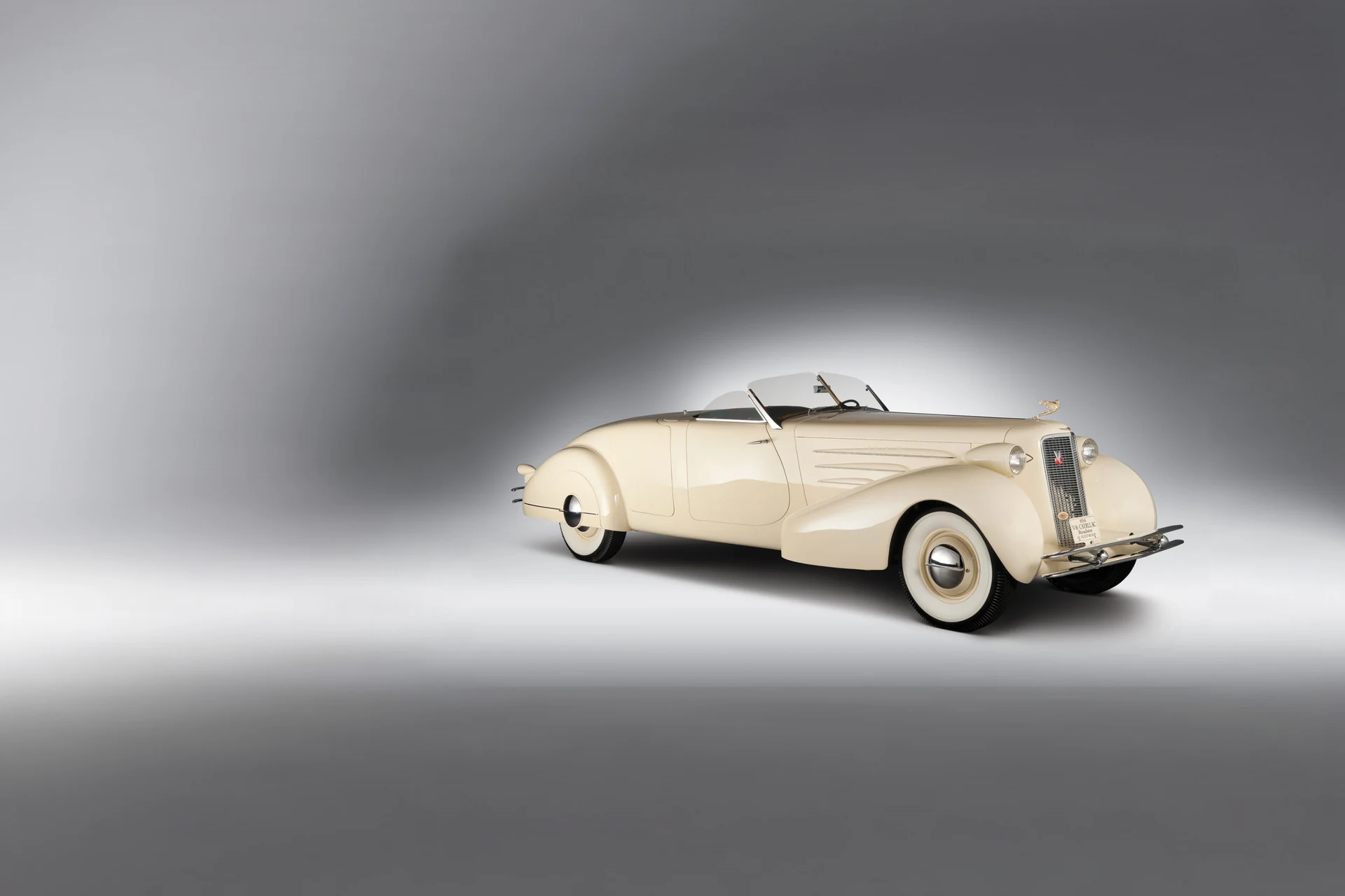 Cadillac V-16 родстер 1934 года кремового цвета на белом студийном фоне, три четверти спереди, нос вправо