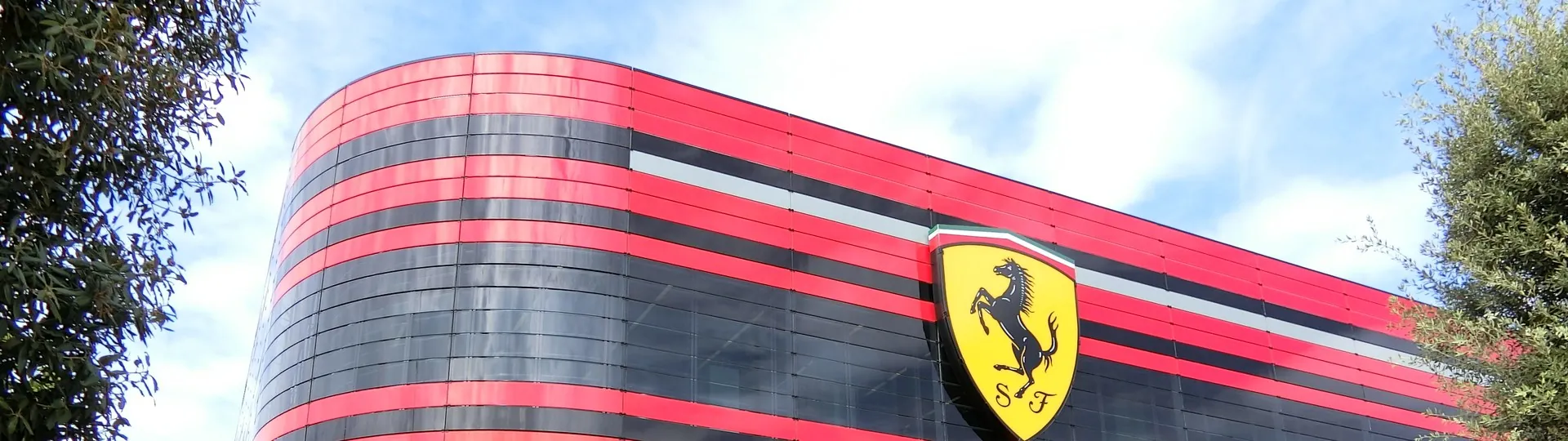 Фасад гоночного департамента Ferrari в Маранелло с красными полосами и жёлтым щитом с гарцующим конём