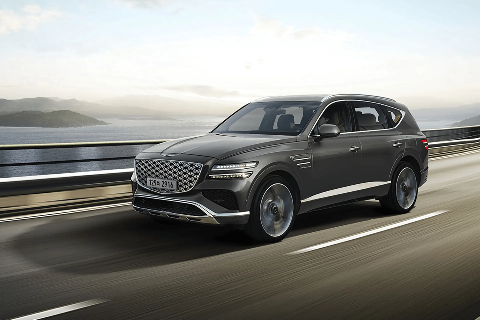 Genesis GV80 в движении по приморской дороге днём, вид спереди