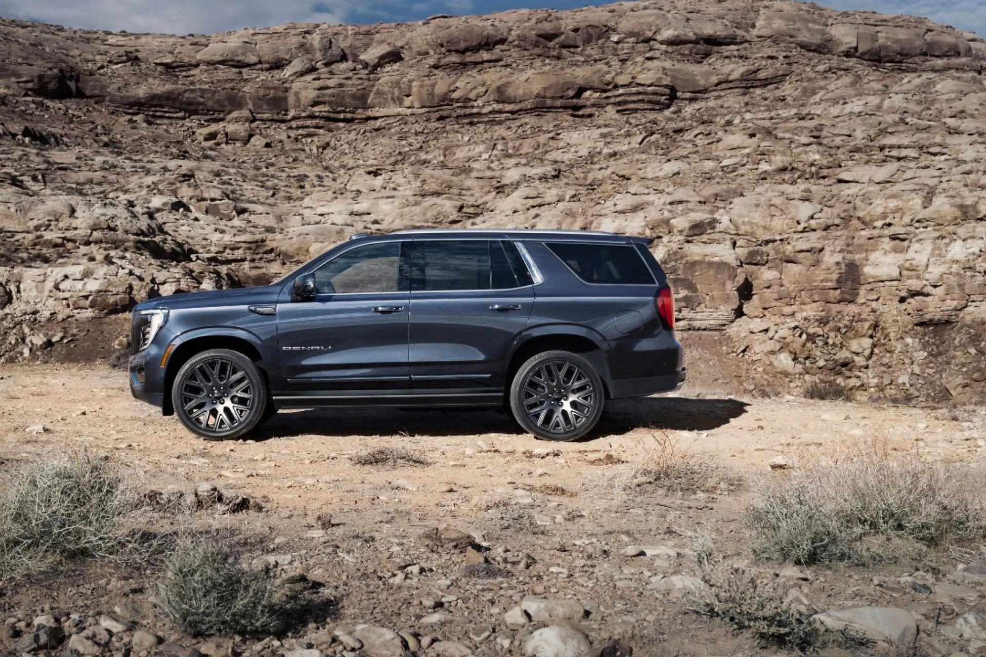 GMC Yukon Denali Ultimate в профиль на грунтовой дороге в каньоне