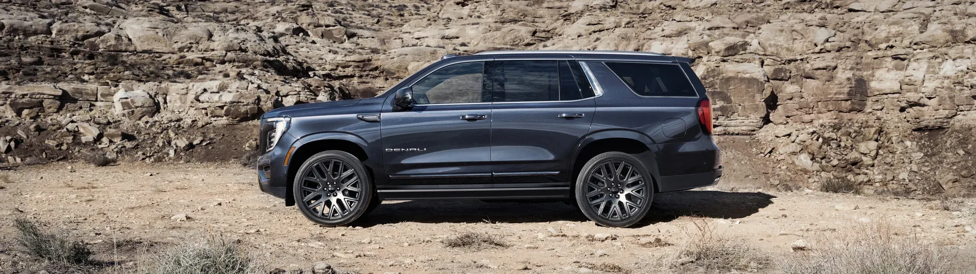 Тёмно-синий GMC Yukon Denali в профиль на фоне каньона