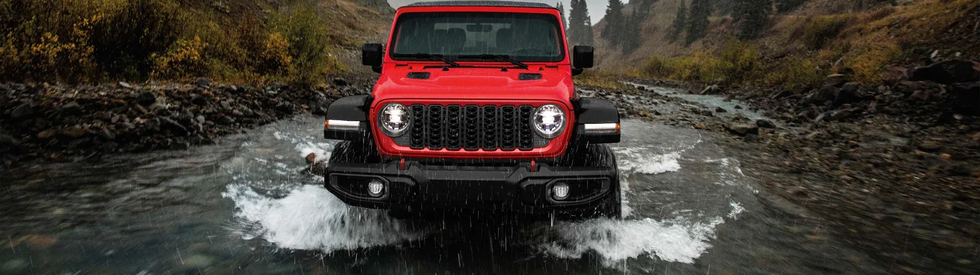 Красный Jeep Wrangler Rubicon пересекает горную реку
