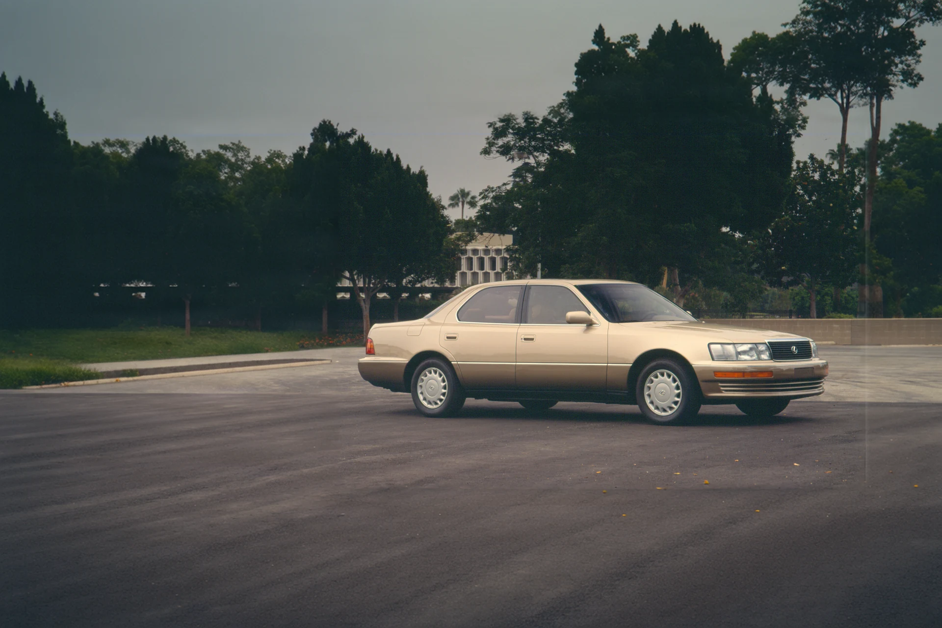 Lexus LS 400 первого поколения 1990 модельного года, цвет шампань, на пустой площади перед зданием; пресс-фото Lexus USA.