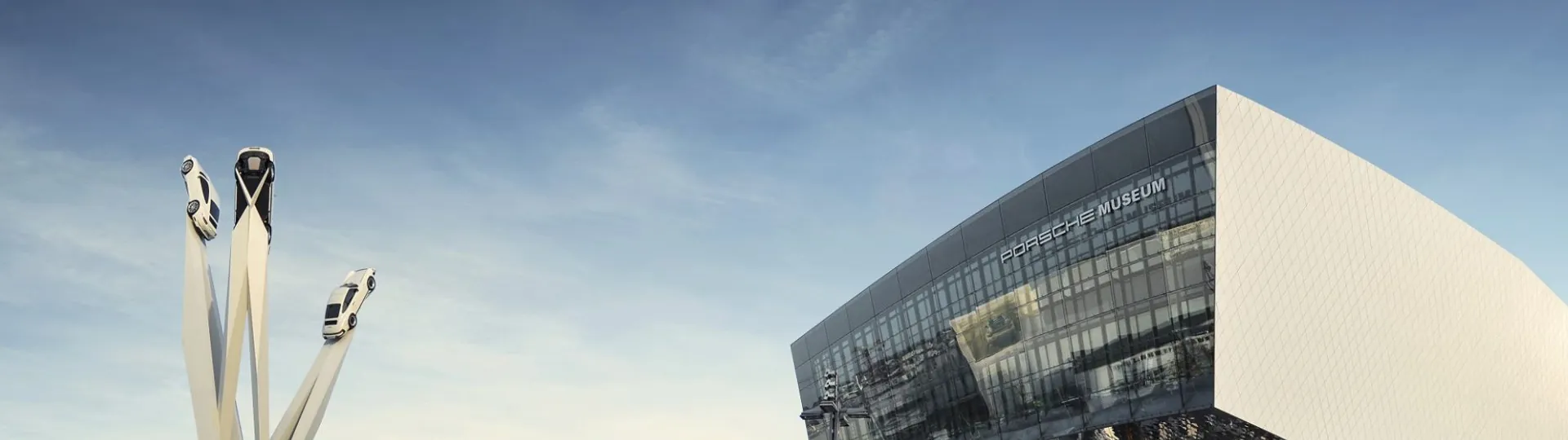 Музей Porsche в Цуффенхаузене с надписью Porsche Museum на фасаде и скульптура из трёх 911