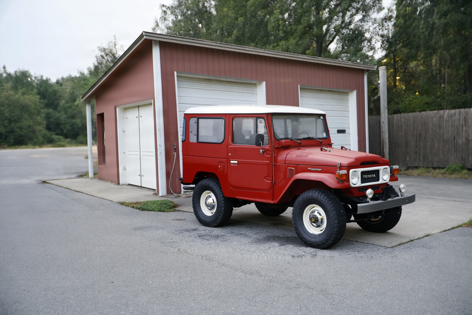 Красный Toyota Land Cruiser FJ40 1982 года у гаража